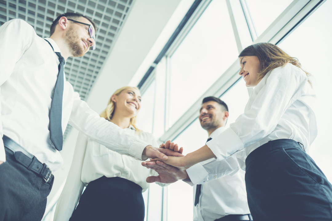 The four business people hold hands together